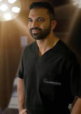Man with beard wearing black v-neck scrubs in a professional studio setting with warm lighting